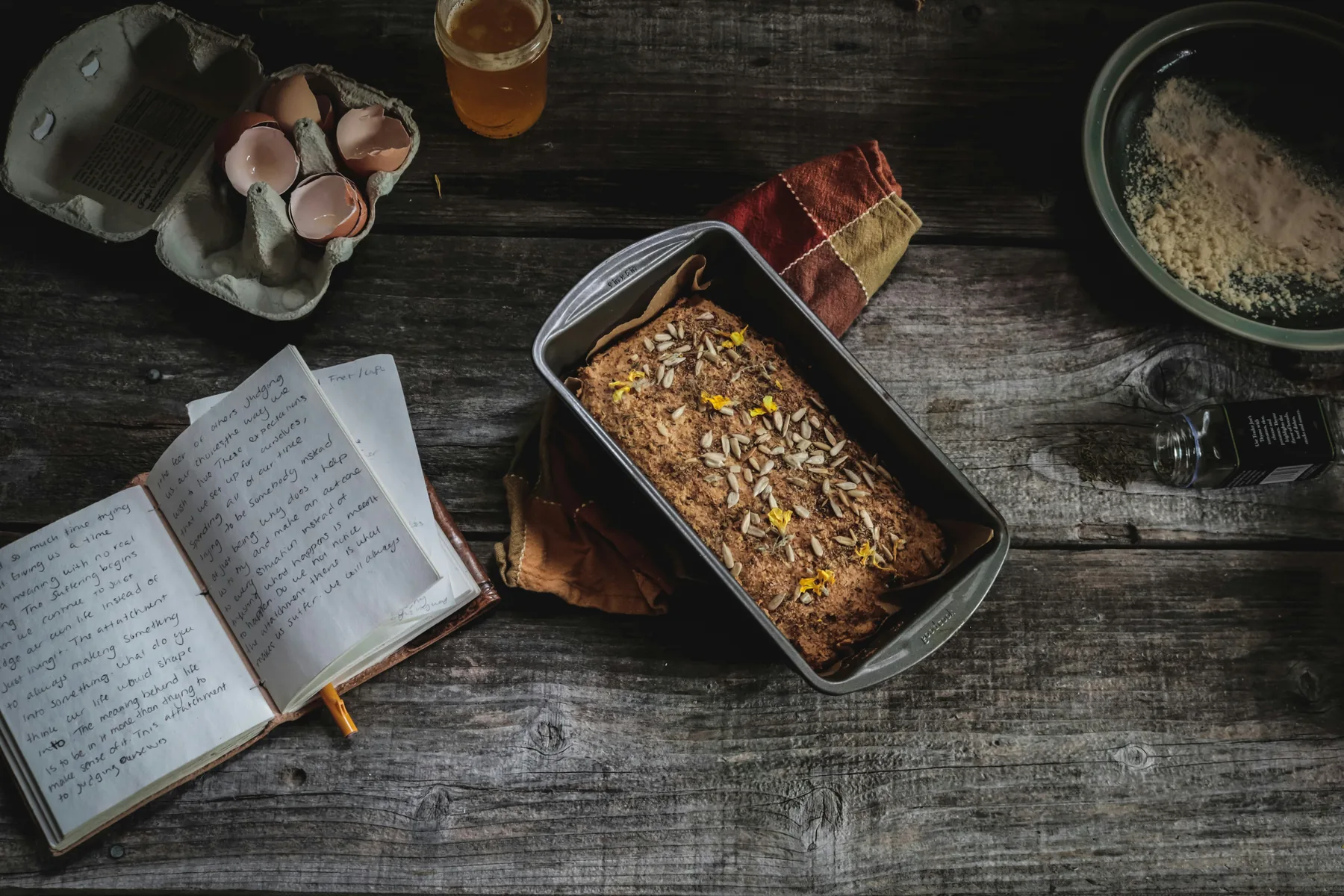 Handwritten recipe book beside a freshly baked loaf on a wooden table