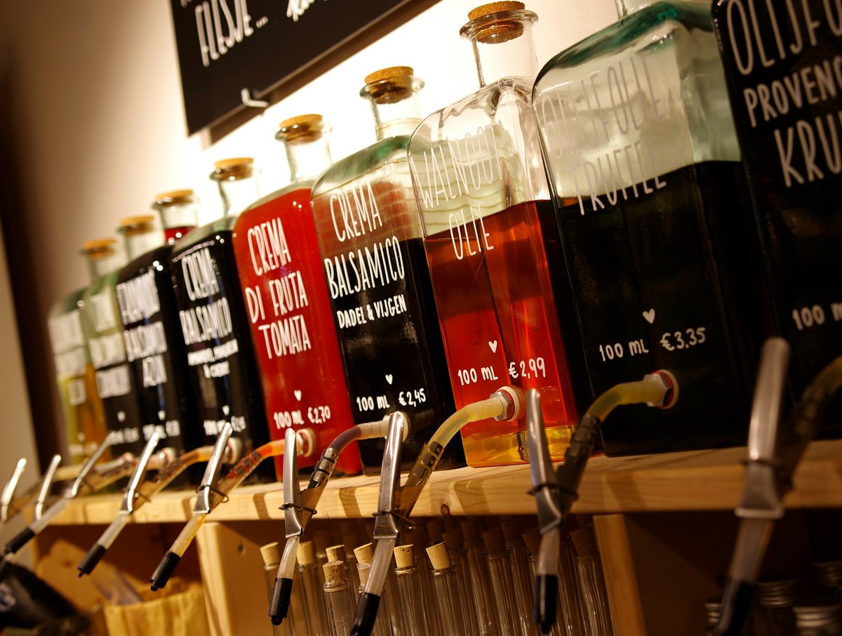 A row of refill bottles labelled with different vinegars and oils.