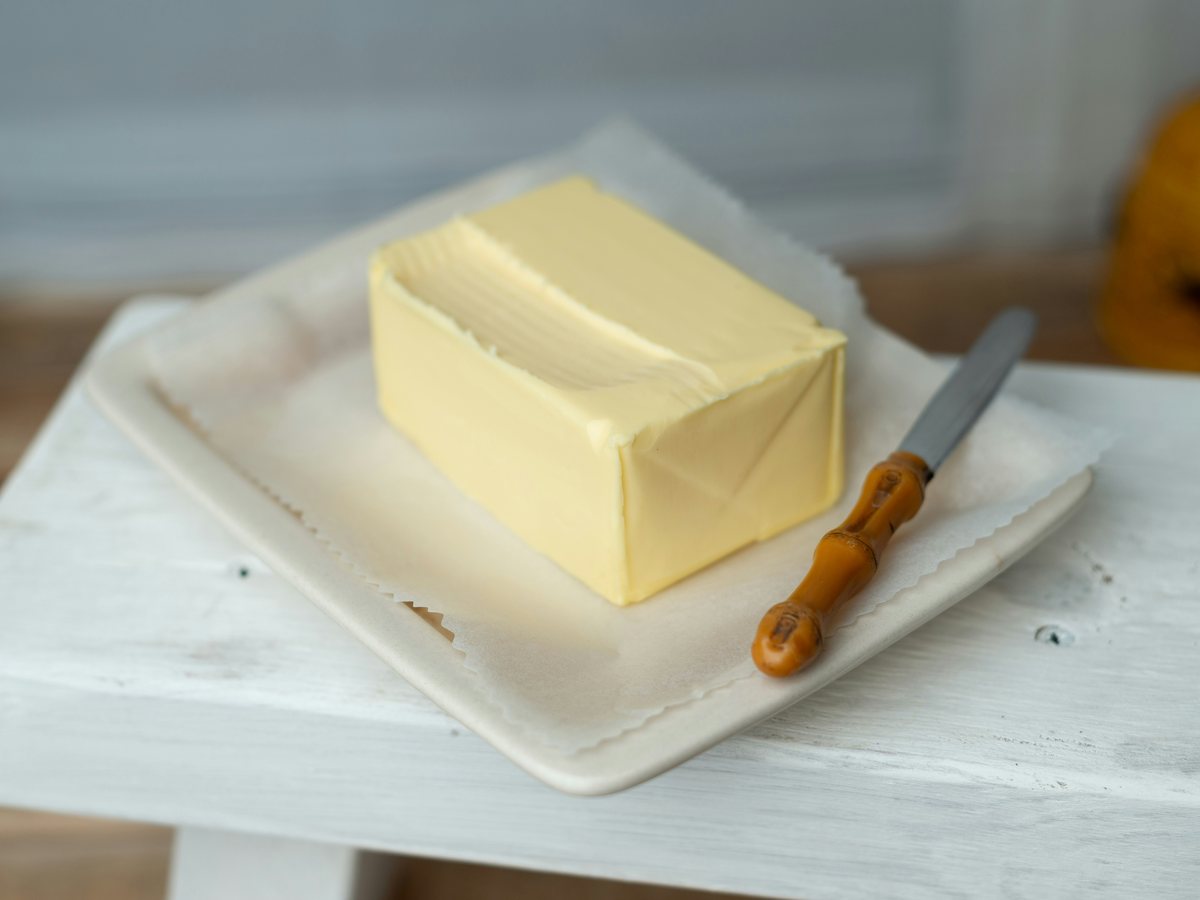 A block of butter beside a knife on a white tray.
